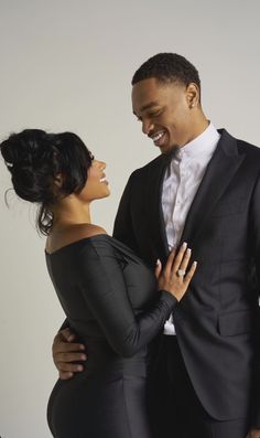 a man and woman in formal wear posing for a photo together, with their arms around each other's shoulders