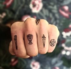 a person's hand with four different tattoos on their fingers and one is pointing at the camera