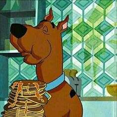 the scooby dog is sitting on top of pancakes and looking up at him