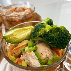 broccoli, chicken and other vegetables in a bowl on a table next to bowls of food