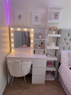 a white vanity with lights on it in a bedroom next to a bed and desk