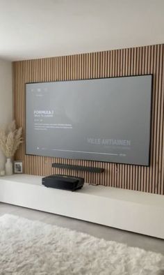 a flat screen tv mounted to the side of a wall in front of a white rug