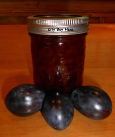 three plums sit next to a jar of preserves