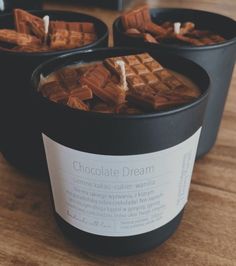 three black buckets filled with chocolate and marshmallows on top of a wooden table