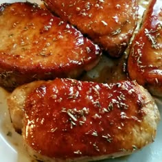 four pieces of meat covered in sauce on a white plate