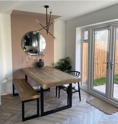 a dining room table with two benches in front of it and a mirror on the wall