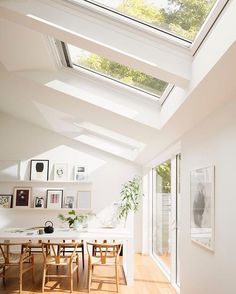 a dining room filled with lots of furniture under a skylight over a wooden floor