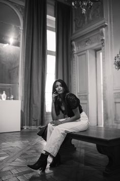 a woman is sitting on a bench talking on her cell phone in an ornate room