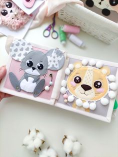 a person holding a small card with some animals on it and cotton balls in the background