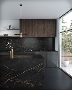 a kitchen with black marble counter tops and wooden cabinetry next to a large window