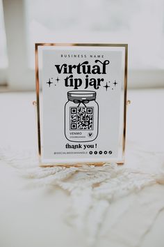 a business card sitting on top of a white tablecloth next to a glass container with qr code printed on it