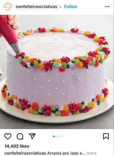 someone is decorating a cake with colorful flowers on the frosting and sprinkles