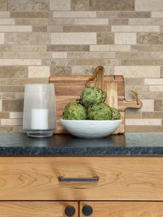 a wooden cutting board sitting on top of a counter next to a bowl filled with green vegetables