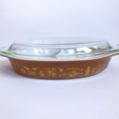 a glass casserole dish with brown and gold designs on the bottom, sitting on a white surface