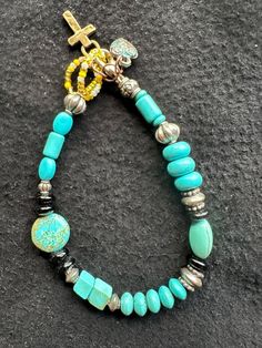 This beaded bracelet features several distinctive elements; different shapes and sizes of turquoise, black glass accent beads, sterling silver beads a clasp closure along with a bronze heart charm and a brass cross charm.  The overall design combines bohemian style and southwestern elements.  The turquoise is the dominant color, creating a bright, eye-cathcing piece, while the black beads and silver accents provides a nice contrast..   It can fit a wrist about 7-1/2 to 8",   My jewelry is unique Bohemian Turquoise Beaded Bracelets With Black Beads, Bohemian Turquoise Beaded Bracelet With Black Beads, Turquoise And Black Beaded Bohemian Bracelet, Adjustable Turquoise Beaded Dangle Bracelets, Blue Bracelet With Black Beads, Blue Bracelet With Black Beads Jewelry, Handmade Black Bohemian Charm Bracelet, Adjustable Turquoise Jewelry With Black Beads, Turquoise Beaded Bracelets With Black Beads