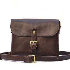 The Solid Leather Co Slimline Purse adds a dash of retro flair to any outfit. This relaxed yet refined carry-all crossbody bag is practical enough to become your next wardrobe staple. The Solid Leather Slimline Purse has been updated with a new, softer leather. It features the same great, efficient design but we are utilizing a softer, pebbled/tumbled full grain vegetable tanned cowhide leather. The result is a fantastic purse with a great feel and texture to it. Right out of the box it has a broken-in feeling as if you've been using it for years already.  ↣ The solid brass buckle strap opens to an unlined compartment with plenty of room for an iPad Mini or similar size tablet. The exterior slot pocket along the back of this shoulder bag allows quick access to your transit pass or coffeeho Brown Leather Satchel, Leather Company, Leather Cross Body Bag, Tan Cowhide, Veg Tan Leather, Leather Cross, Brass Buckle, Bag Vintage, Cross Body Bag