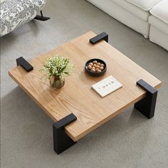 a coffee table with two black legs and a bowl of nuts on it in front of a couch