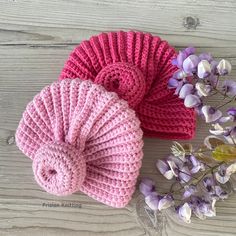 two crocheted hats sitting next to each other on top of a wooden table