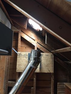 a metal pipe is in the corner of a room with wooden walls and beams on it