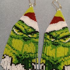 a pair of green and white beaded earrings with an image of the grin face