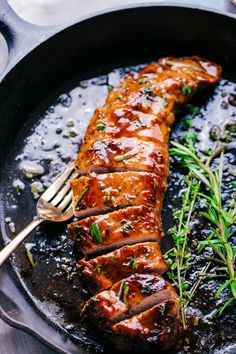 a piece of meat is being cooked in a skillet with some garnish