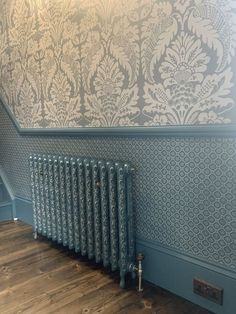 a radiator in the corner of a room with blue walls and wallpaper