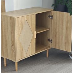 a wooden cabinet sitting on top of a hard wood floor next to a potted plant