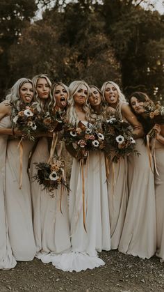 a group of women standing next to each other wearing dresses and holding bouquets in their hands