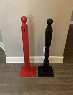 two black and red poles standing next to each other on the floor in front of a white wall