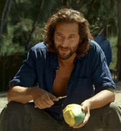 a man sitting on the ground holding an apple