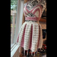 a crocheted dress is displayed on a mannequin in front of a window