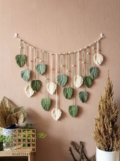 a wall hanging with green leaves on it next to a potted plant and other items