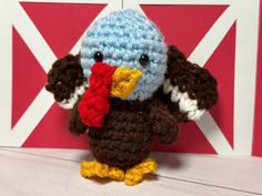 a crocheted stuffed bird with a red, white and blue scarf around its neck