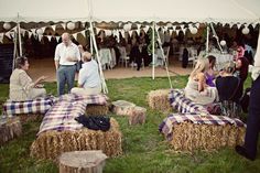 people sitting on hay bales under a tent