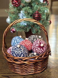 a basket filled with knitted ornaments next to a christmas tree