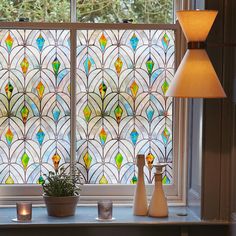 a stained glass window with two vases and a lamp next to it