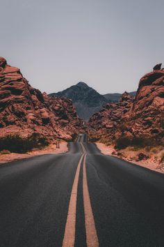 an empty road with mountains in the background