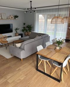 a living room filled with furniture and a flat screen tv mounted on the wall above a wooden table