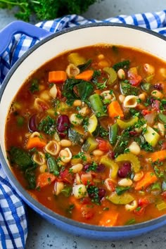 a bowl of soup with beans, spinach and carrots in it on a blue towel