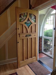 an open wooden door with stained glass on the front and side panels, leading to a stairway