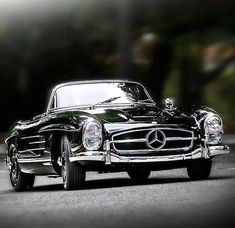 a black and white photo of a classic mercedes benz coupe parked on the side of the road