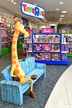 a toy store with toys on the shelves and a fake giraffe sitting on a bench