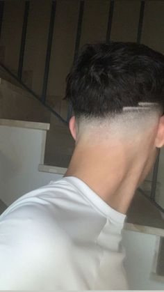 a man with a shaved back undercut standing in front of stairs