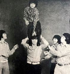 an old photo of some people holding a child on their shoulders