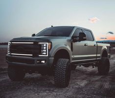 a silver truck parked on top of a dirt road