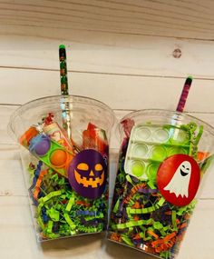 two plastic cups filled with candy and halloween decorations