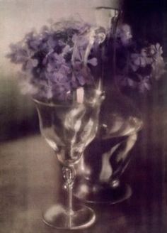 two glass vases with purple flowers in them