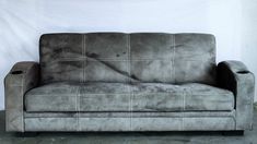 a gray couch sitting on top of a cement floor