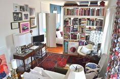 a living room filled with lots of furniture and bookshelves covered in pictures on the wall