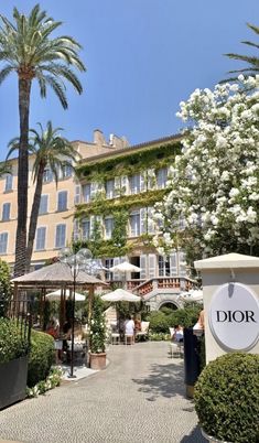 the entrance to dior's restaurant with palm trees and white flowers in front